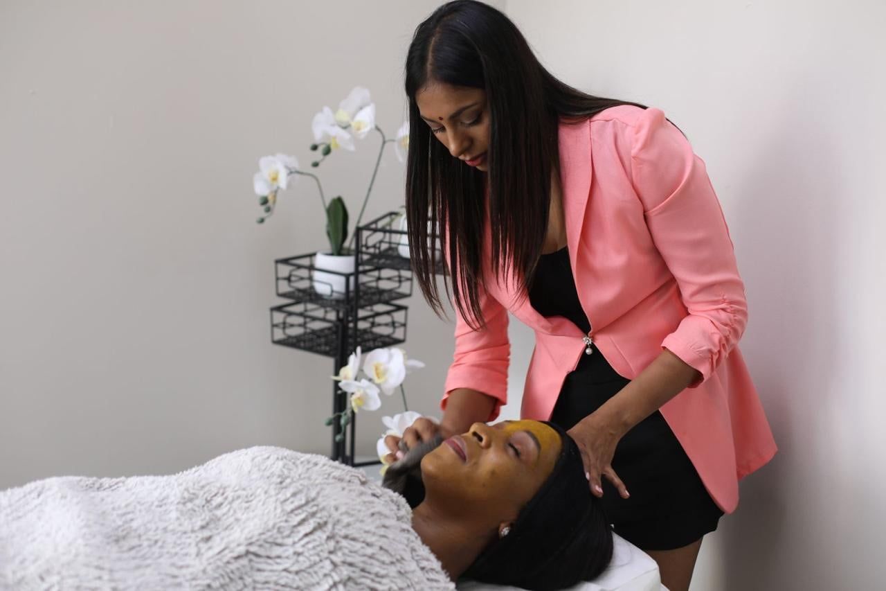 Komona applying a turmeric face pack during an Ayurvedic facial